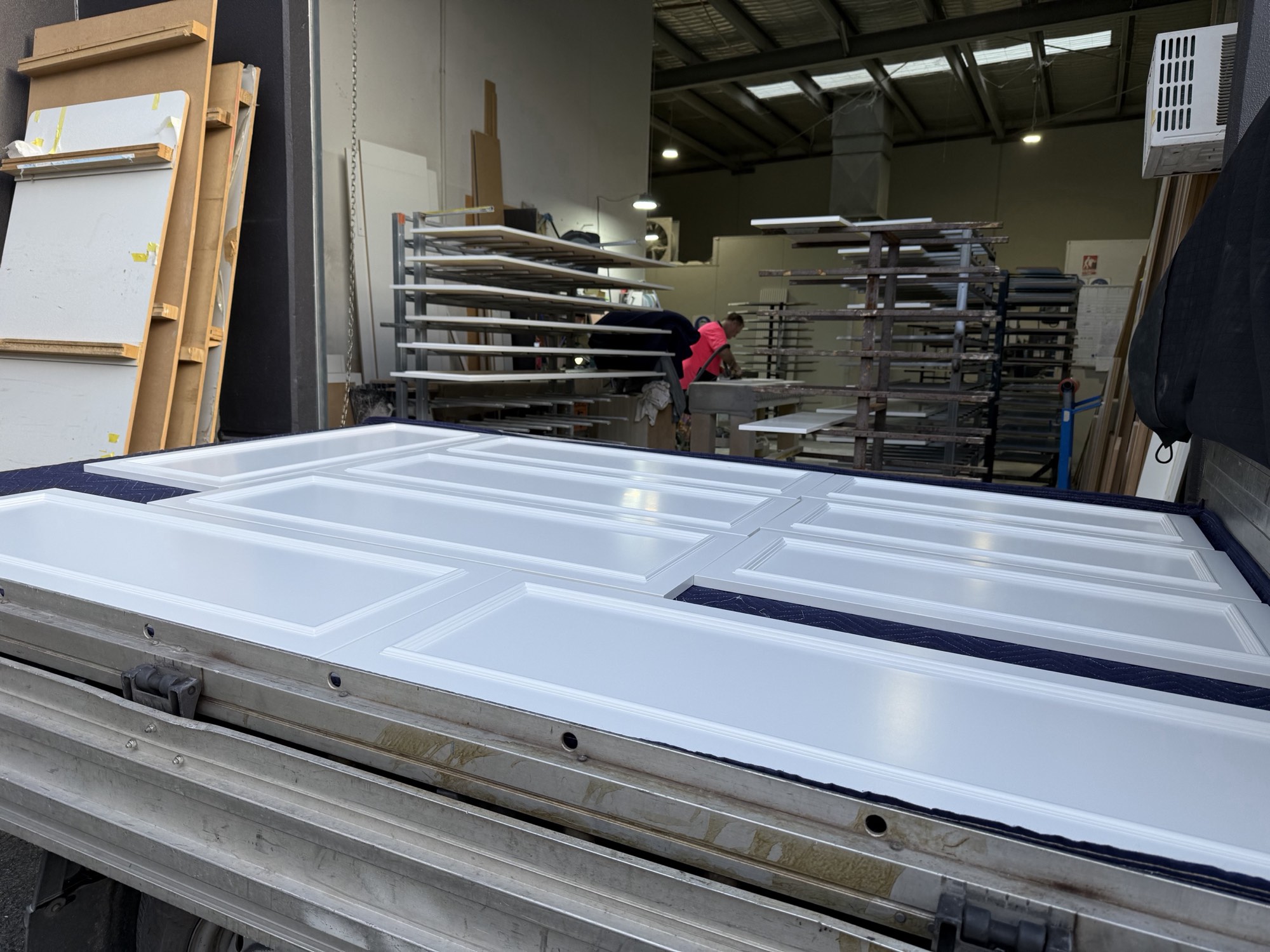 Finished moulded doors in satin white loaded in the van, spray racks and the Molendinar workshop behind
